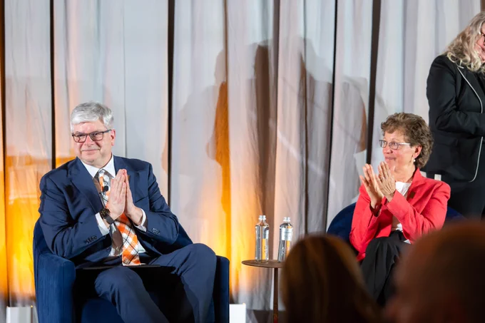 Two people clapping from a stage