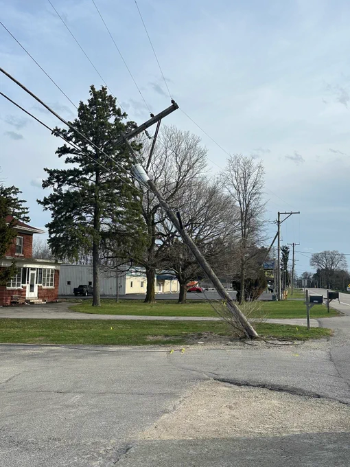 A utility pole stands at an angle after being impacted by strong winds.