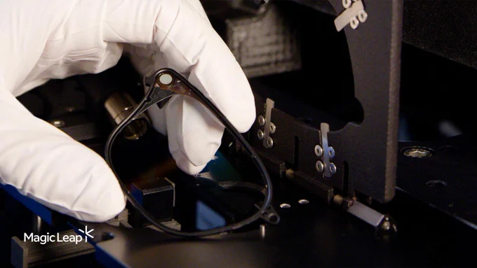 A Magic Leap technician holds a waveguide after it has been inserted into a polymer frame. 