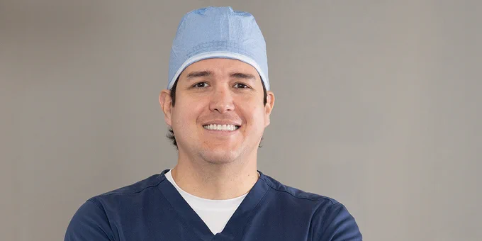 Male doctor or nurse dressed in scrubs posing for a photo.