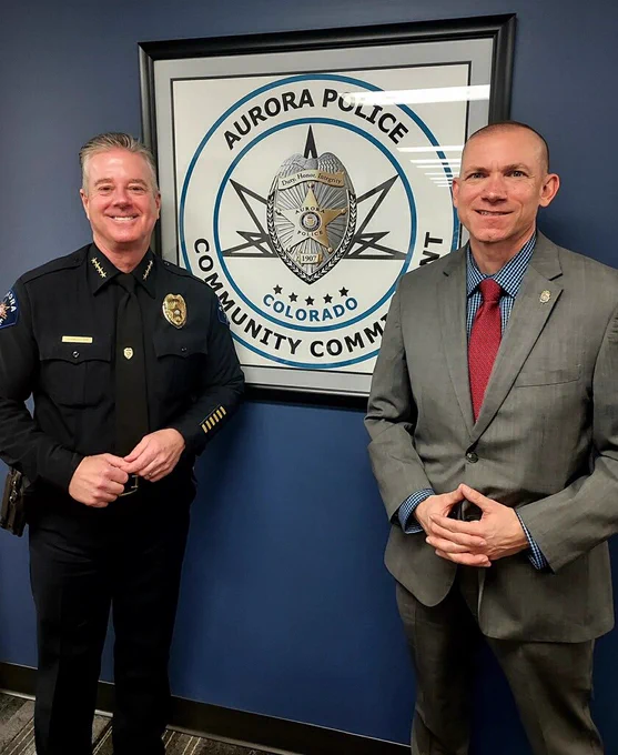 Aurora Police Chief Chamberlain and DEA SAC David Olesky pose in front of APD seal