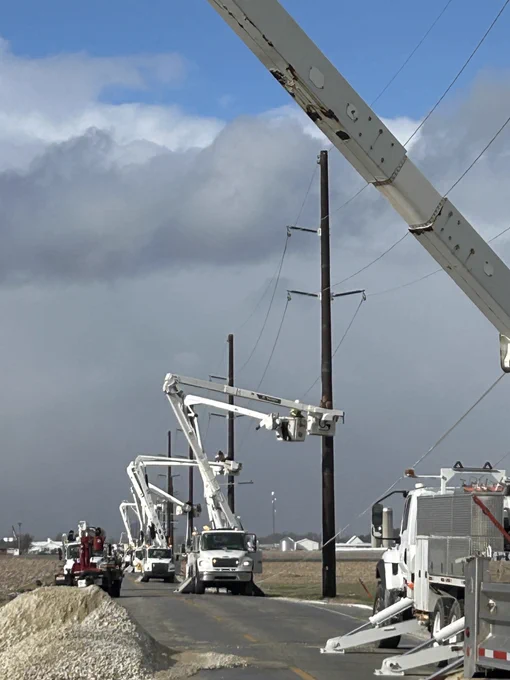 multiple utility trucks in a row working to replace several transmission poles.