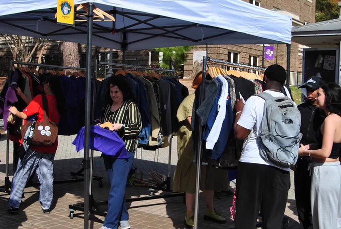 People browsing clothes on racks under a pop-up tent on SFA's campus.