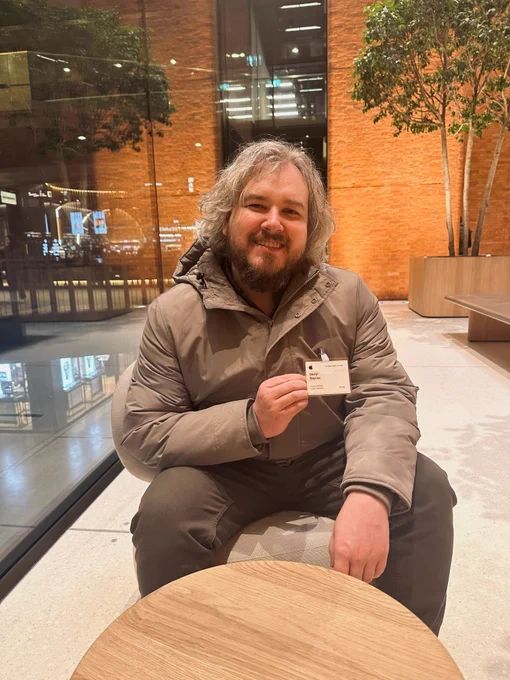 Darryl is holding his Apple Vistor Badge in the office reception.