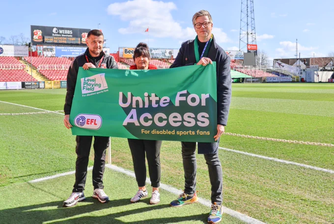 Three people holding a green flag with the words Unite for Access