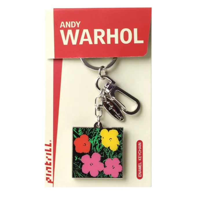 A keychain with a square enamel pendant featuring colorful flowers, inspired by Andy Warhol's art, is attached to a branded card reading "Andy Warhol" and "PINTRILL."