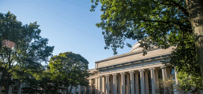 A building at MIT with trees on a clear day.