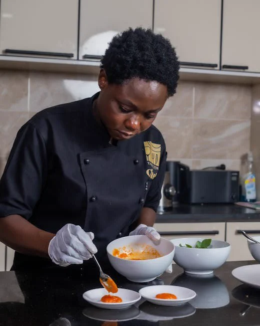 Chef expertly garnishes plates with mashed potatoes and sauce in a professional kitchen setting.
