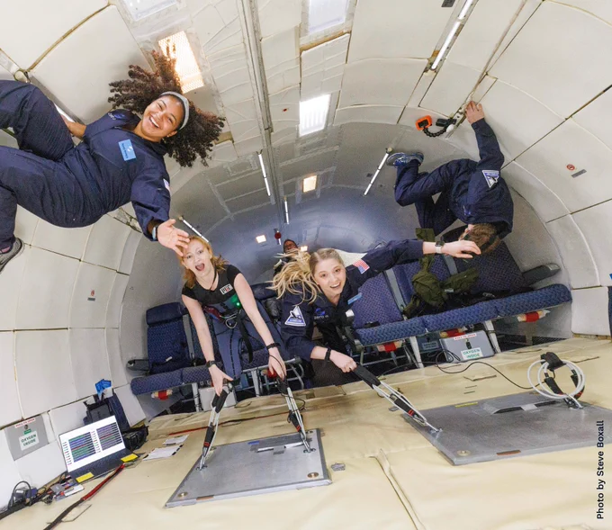 Allison and others float inside a tunnel-like area. It is a Zero-G parabolic flight involved in a study investigating a wearable gravity countermeasure suit (“Skinsuit”).
