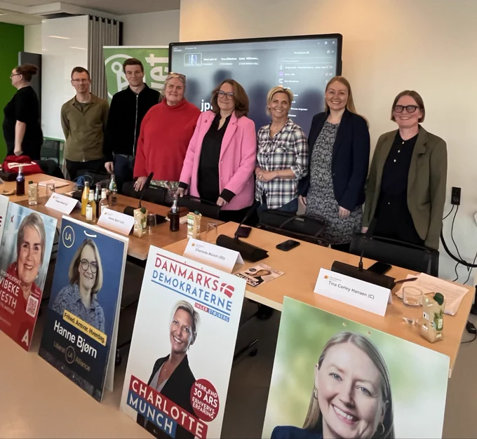 Panelet af folketingskandidater og Diana står bag en række af borde. Foran bordene står kandidaternes valgplakater. Fra venstre står Tim Wodskou, Sigurd Agersnap, Vibeke Westh, Hanne Bjørn, Charlotte Munch, Tina Cartey Hansen og Diana.