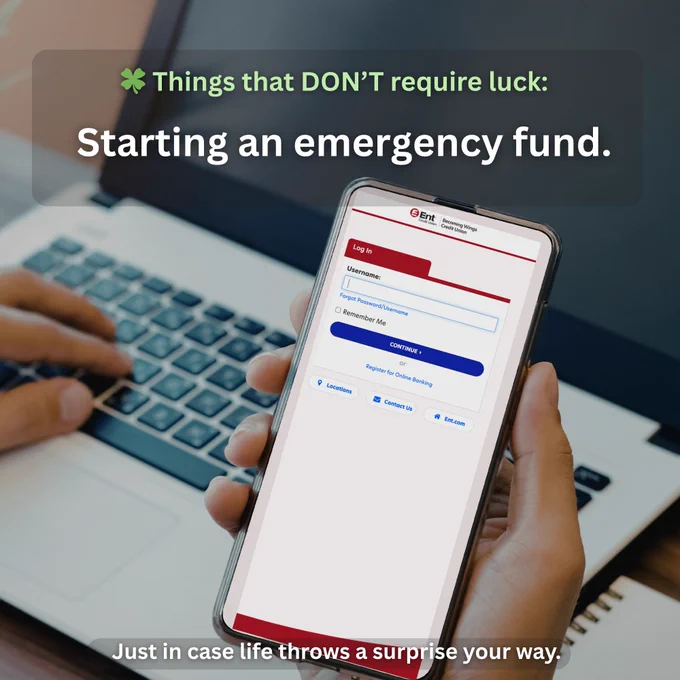 A person using a laptop is holding a phone displaying the login page of Ent Credit Union. The text reads, "Things that DON’T require luck: Starting an emergency fund. Just in case life throws a surprise your way.