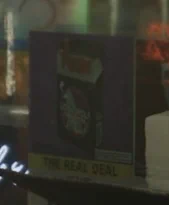 A demo screenshot from Resident Evil Requiem with "DLSS 5 OFF", showing a sign in a store window for what appear to be a pack of cigarettes on a purple background. Beneath, the sign reads "THE REAL DEAL" against a yellow background.