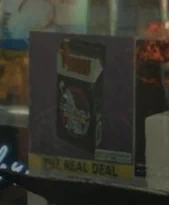 A demo screenshot from Resident Evil Requiem with "DLSS 5 ON", showing a sign in a store window for what appear to be a pack of cigarettes on a purple background. Beneath, the sign reads "PNZ REAL DEAL" against a yellow background. The image is sharpened, and texture is added to the purple background.