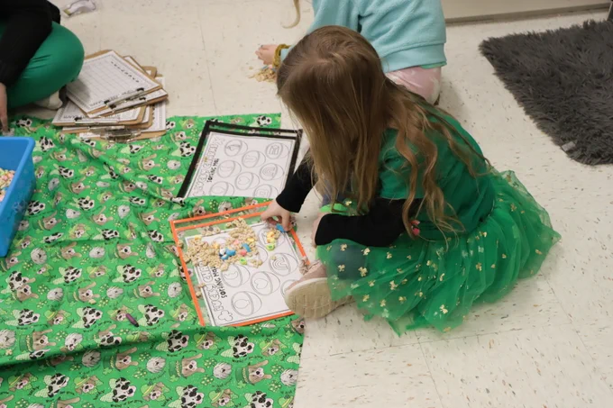 student dressed in green on a green sheet doing an activity 