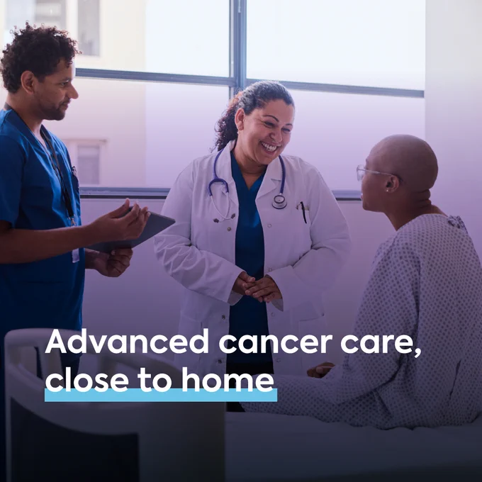 Clinicians speaking with patient. Text reads \"Advanced cancer care, close to home\"