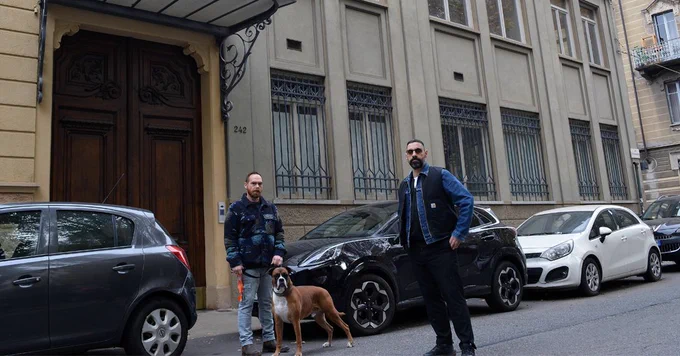 Two people and a dog stand outside a building.