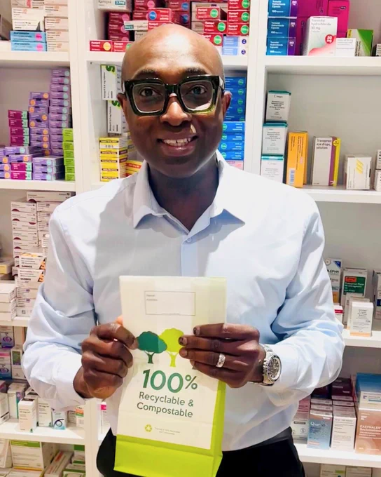 Photo of a local pharmacist smiling, holding a prescription bag.