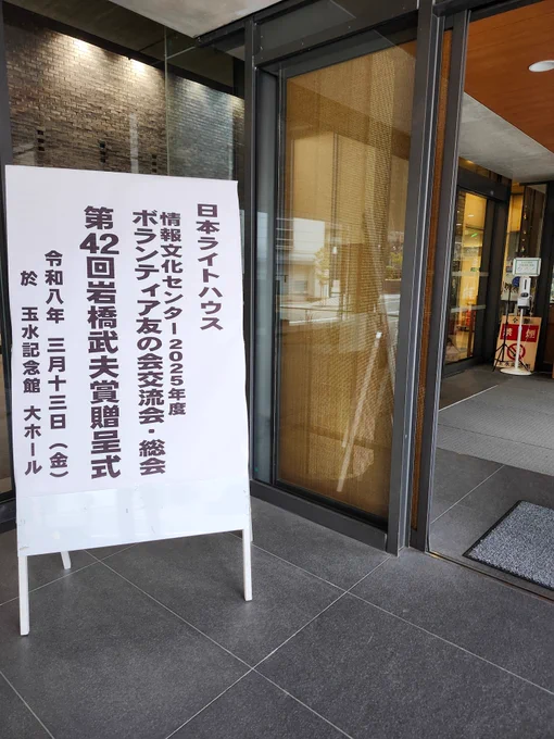 会場入り口の写真です。
扉の前に立て看板があり、交流会と岩橋武夫賞贈呈式の案内が記載されています。