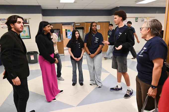 A group of  students and Lt. Gov. Aruna Miller standing in a school hallway engaged in a discussion.
