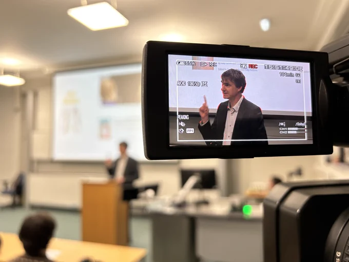 Colour photo of a camera viewfinder recording Professor Gordon Lynch as he speaks stood at the lectern in the Elizabeth Templeton Lecture Theatre