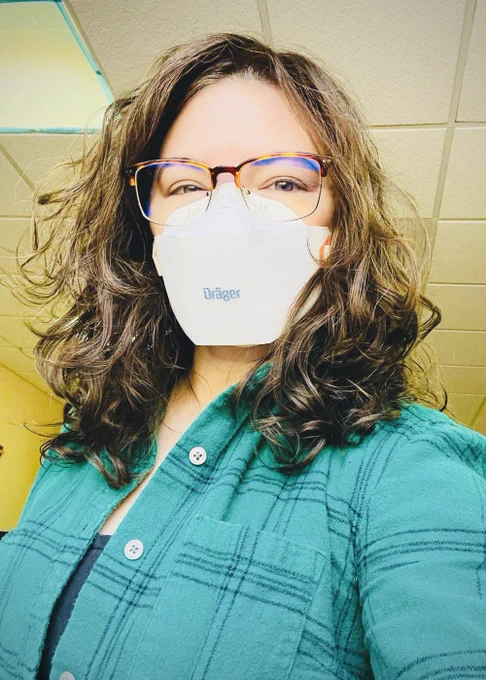 I'm wearing a white draeger n95 respirator, a green plaid flannel shirt, and tortoiseshell and gold frame glasses.
