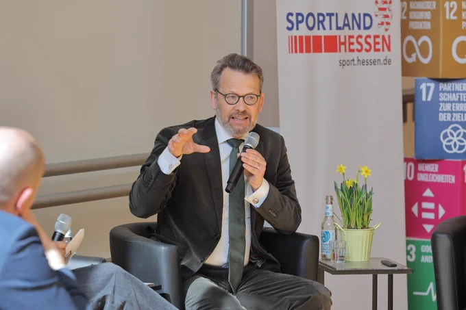 Otto Fricke spricht in ein Mikrofon. Er trägt Anzug und Krawatte und gestikuliert mit seiner rechten Hand. Foto: DOSB