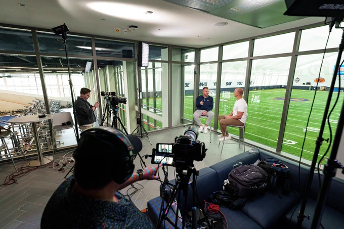 Photos of Head Coach Alex Golesh and Josh pate during an interview at the Woltosz Football Performance Center