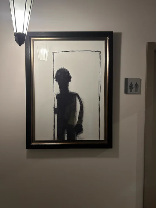 a framed painting of a shadowy figure standing in a doorway. they’ve got a big ass head and arm but a small boxy body