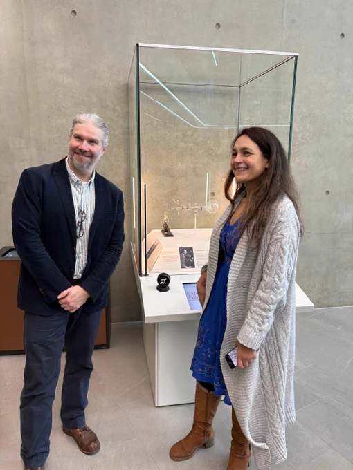 Two people standing beside a glass display case in a modern setting.