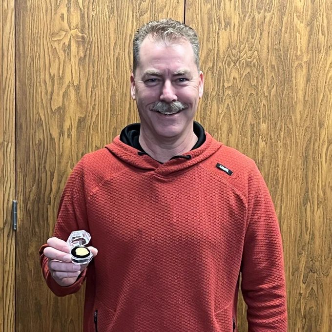 Man with a mustache holding a pin that signifies 35 years of working at the SDDOT.