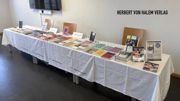 Das Bild zeigt einen Tisch mit Büchern und Werbematerialien des Verlags Herbert von Halem Verlag.