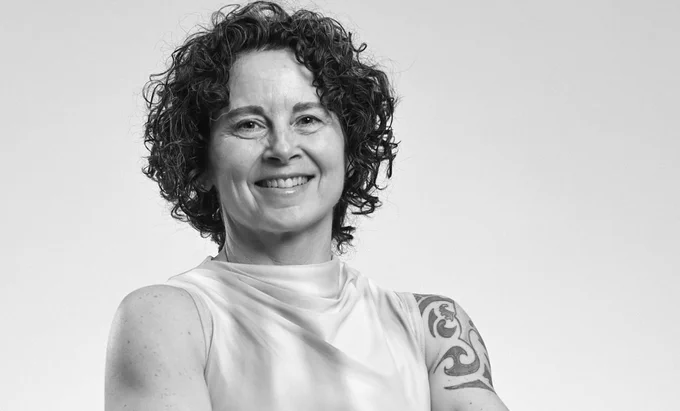 A woman wearing a sleeveless shirt with a visible shoulder tattoo