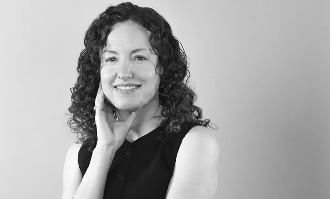 A woman wearing a black sleeveless dress with curly hair
