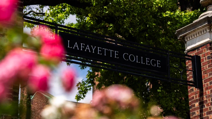 Lafayette College sign framed by blooming pink flowers in the foreground.
