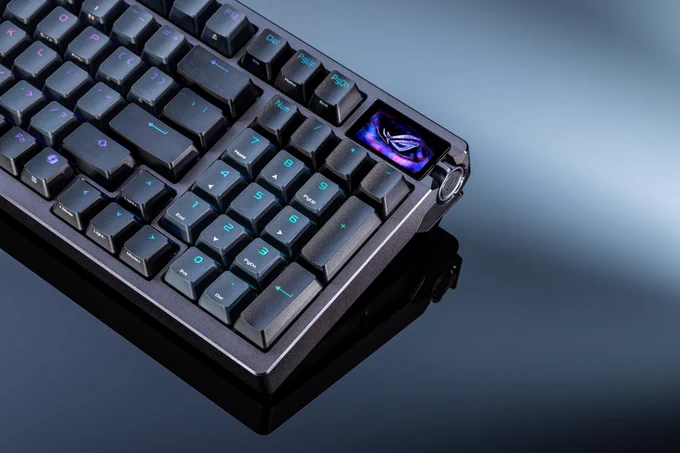 Clavier gaming compact ROG Azoth 96 HE en version noire, avec éclairage RGB bleu, écran OLED intégré affichant le logo ROG et design premium sur une surface réfléchissante.