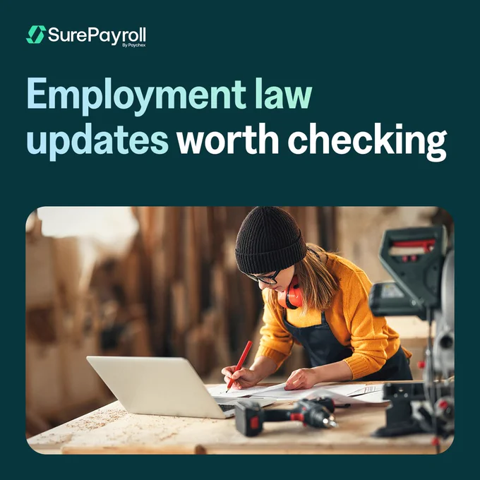 A small business owner in a workshop is working on a laptop surrounded by tools. They are wearing glasses, headphones, a beanie, and an apron. The text reads, "SurePayroll by Paychex – Employment law updates worth checking."