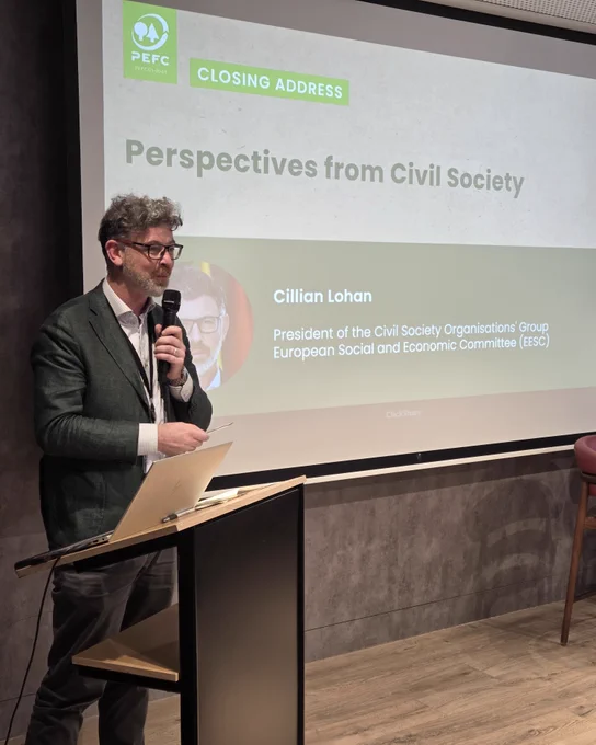 Speaker delivering the closing address titled 'Perspectives from Civil Society' at a conference, standing beside a podium with a laptop.