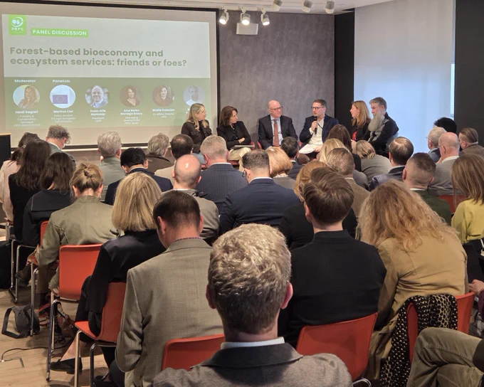 Panel discussion on forest-based bioeconomy and ecosystem services with six speakers addressing an attentive audience in a conference room.