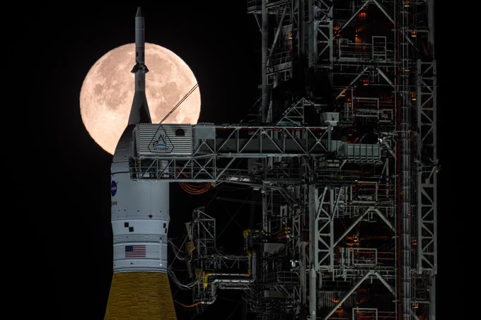 A full moon is seen behind NASA’s Artemis II Space Launch System (SLS) rocket. Image Credit: NASA/John Kraus