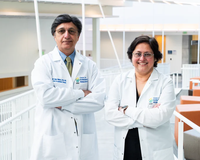 Drs. Sanjay Malhotra (L) and Shivaani Kummar (R) pose for an image while wearing their white research lab coats inside an OHSU facility. 