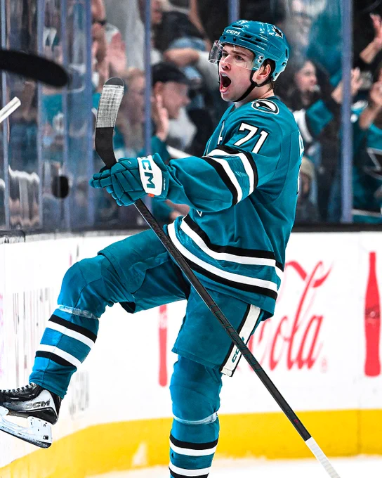 Macklin Celebrini celebrates a goal on ice in a Sharks uniform. 