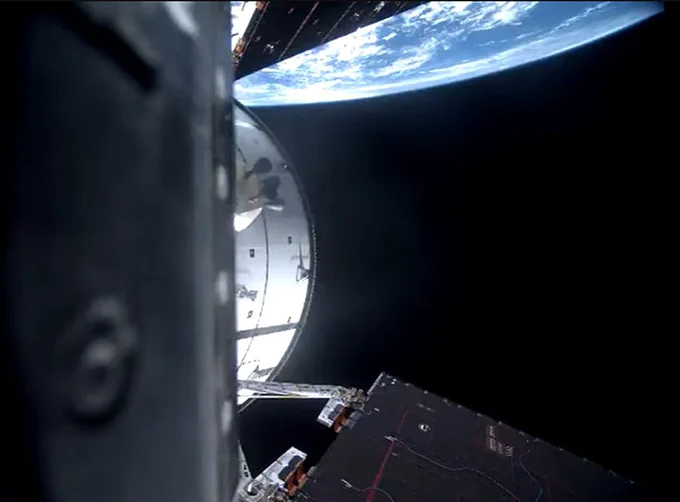 The Orion spacecraft is in the foreground of the image, with a bit of Earth, the \"blue marble,\" at the top. The solar arrays of Orion are seen at the top and bottom of the image. Credit: NASA