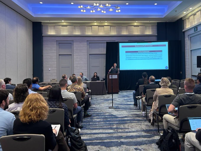 A speaker presenting in front of the session room.