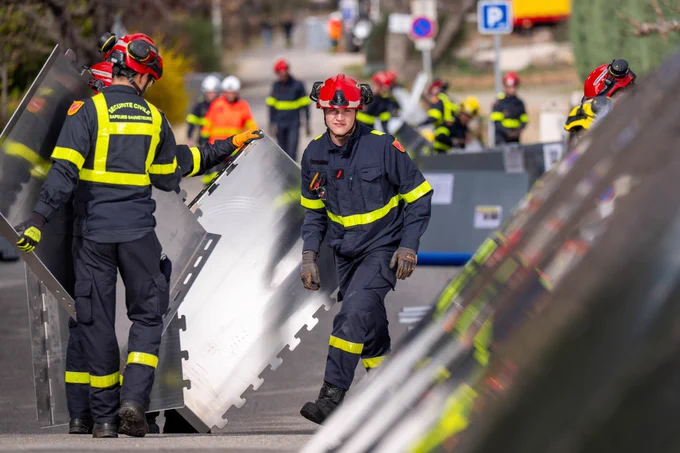 Photographie de sapeurs-sauveteurs de la Sécurité civile en train d'installer un barrage anti-inondation 