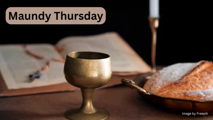 A golden chalice is in the foreground next to a loaf of bread on a tray on the right of the photo. Behind the chalice is an open Bible with a rosary laid over it and a candle in a stand.