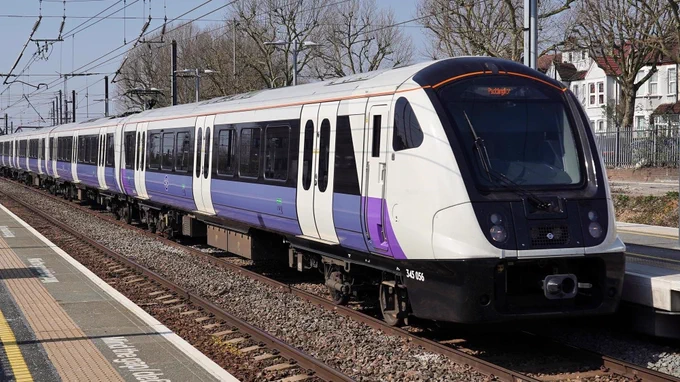 a purple, black and white suburban train looking shiny and very long