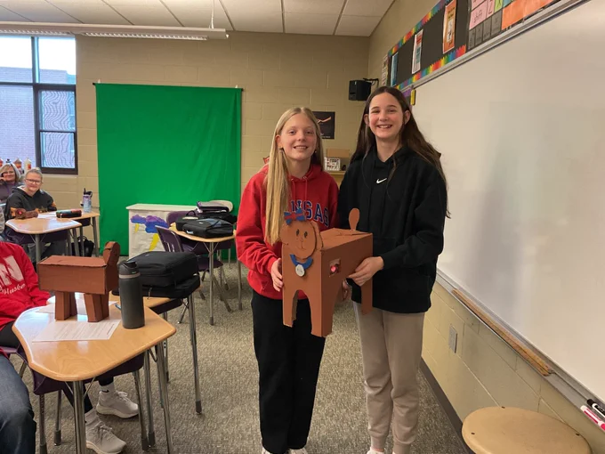 Two students hold up their pet creation: a dog with an olympic medal and "USA" headband! 