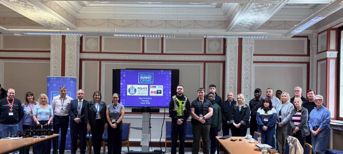 Group photo of police officers and partners in meeting room with presentation ahead of day of action tackling retail crime in Dundee.