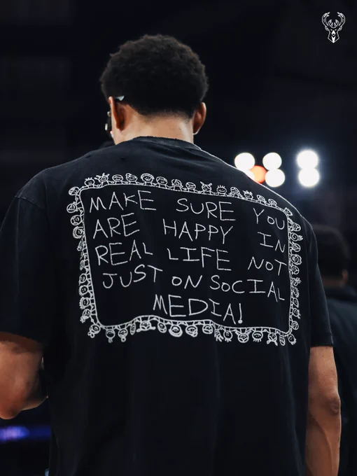 A photo of Ryan Rollins from behind with a shirt that reads, "Make sure you are happy in real life not just on social media!"