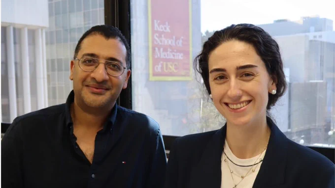 Photo of Mohamed Abou-el-Enein and Amaia Cadinanos-Garai posing for the camera with the Keck School of Medicine logo on a building in the background. (Photo by Anson Cheung)